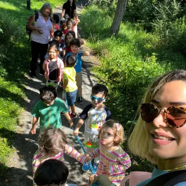Group of children and teachers walking outdoors on a sunny day during a summer camp activity.